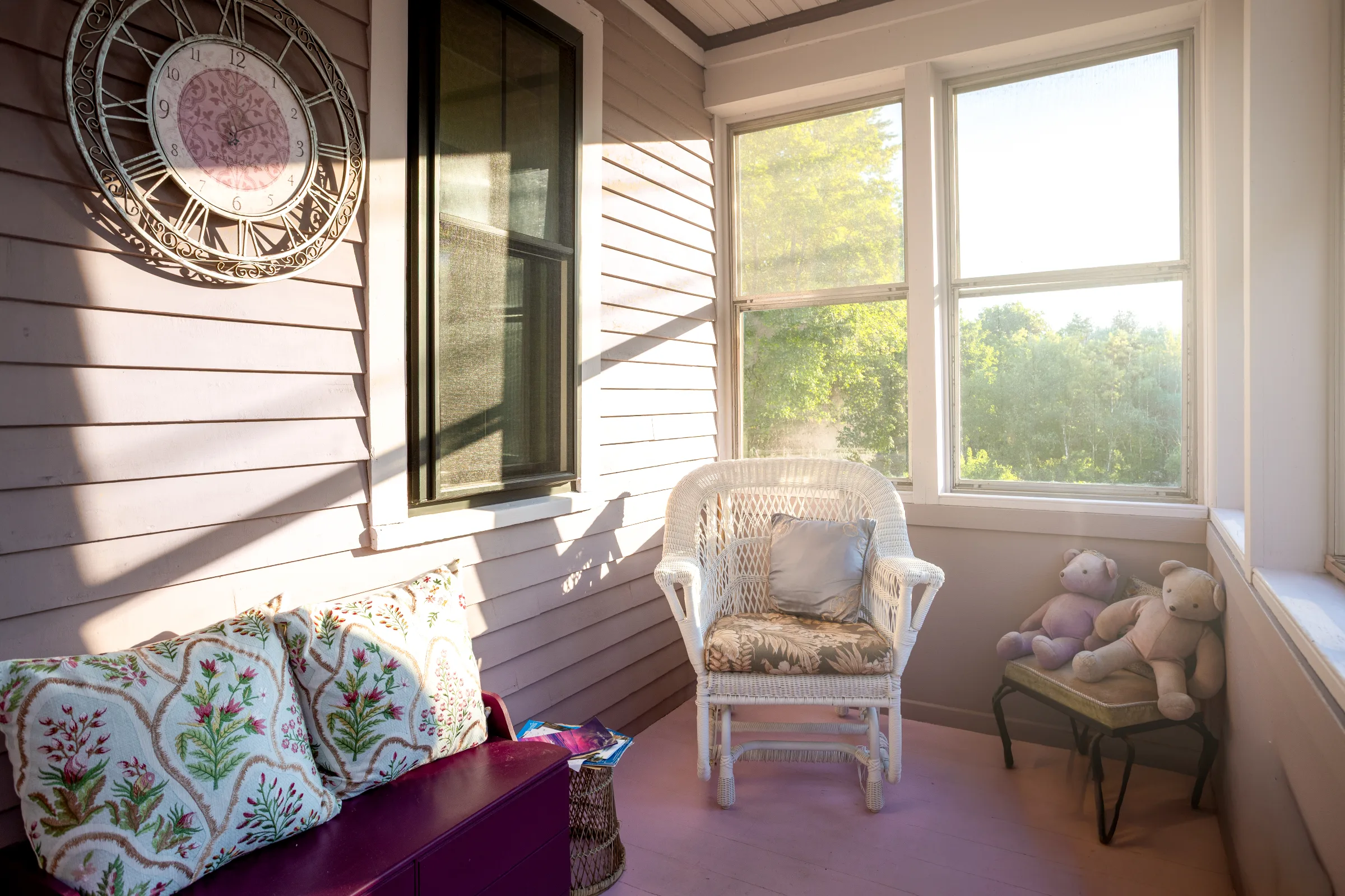 Enclosed porch with mauve siding, light window trim, and white wicker seating