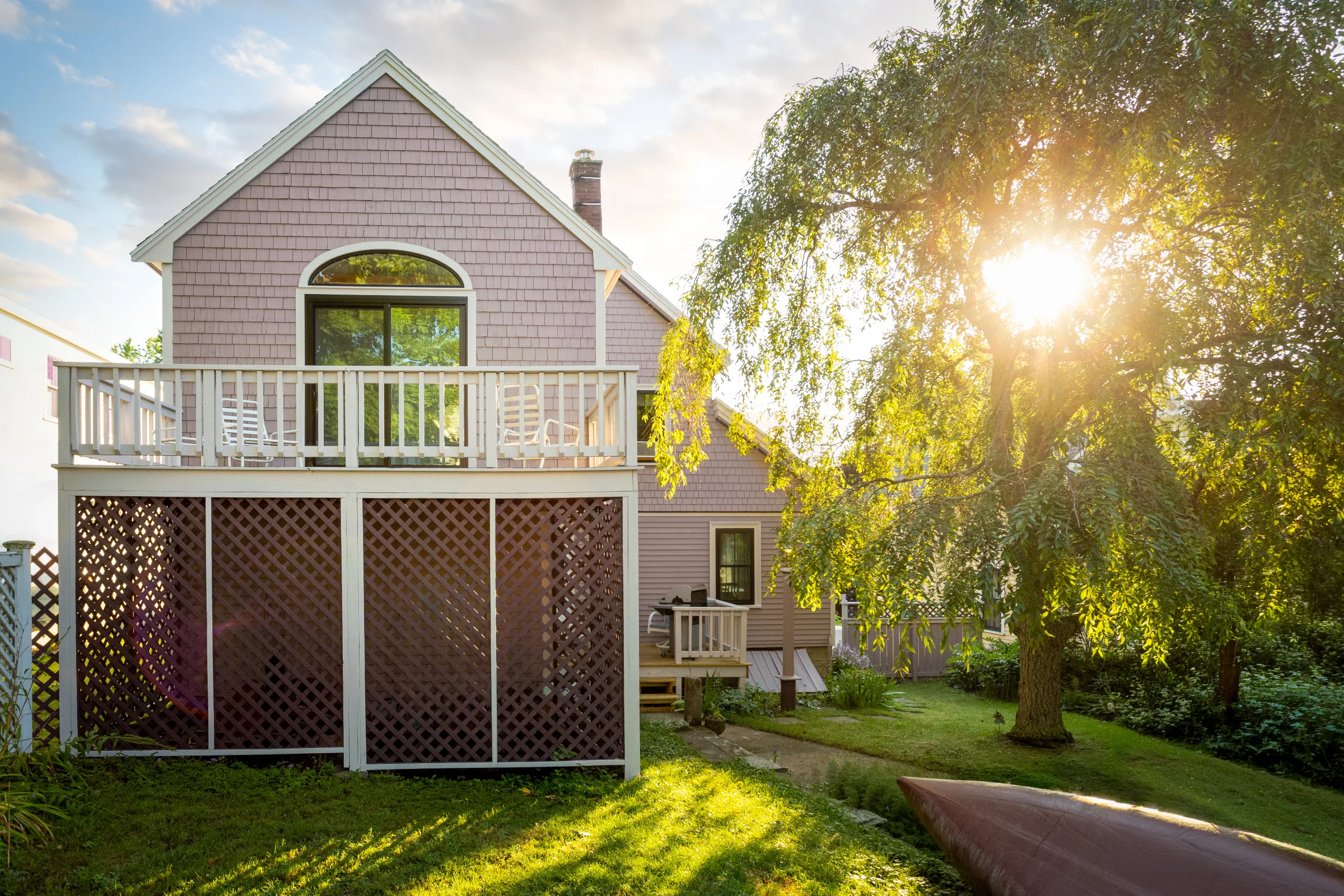 Rear gable with mauve cedar shakes, light deck railing, and purple lattice panels