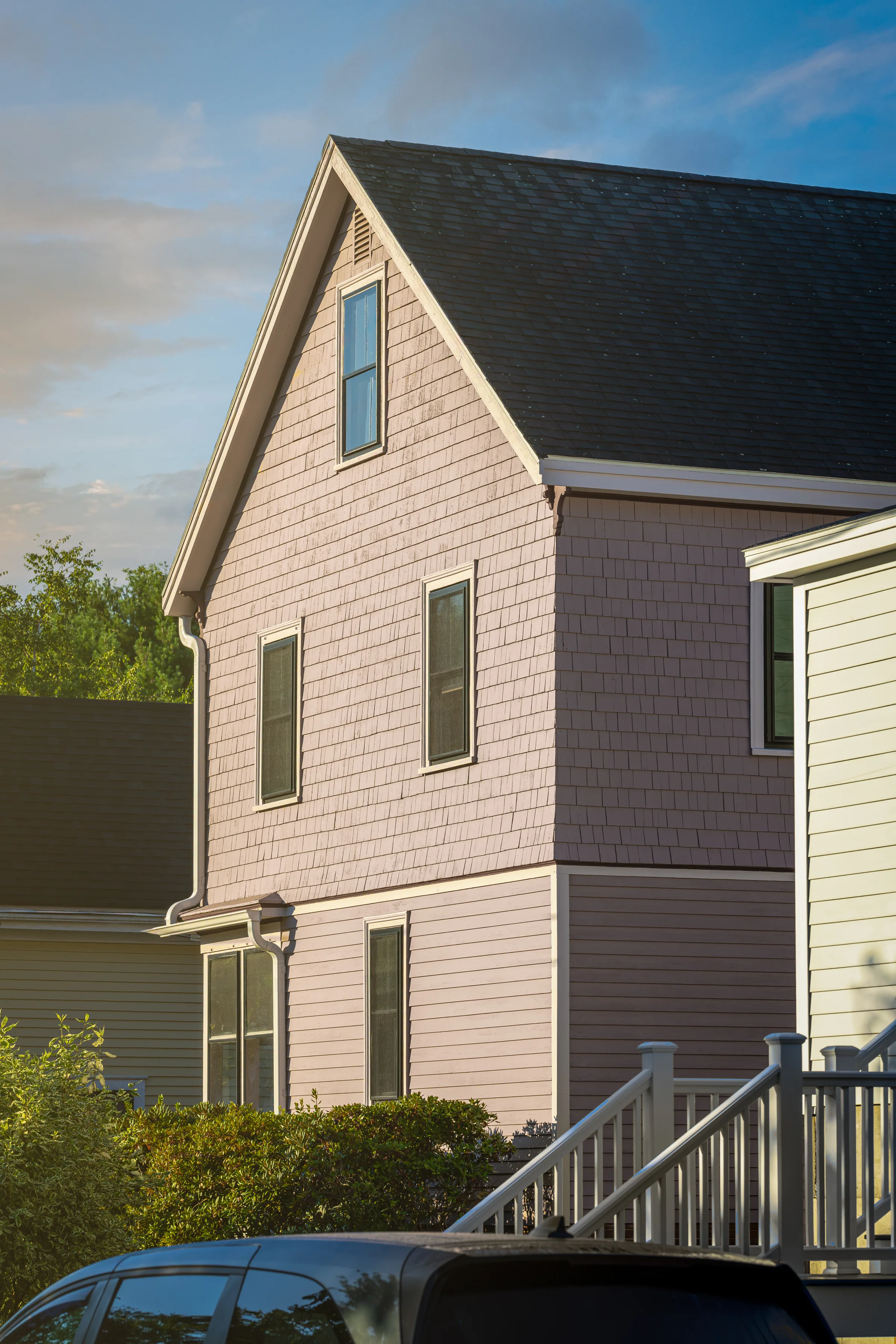 Tall gable wall with painted cedar shakes, horizontal siding, and light window trim