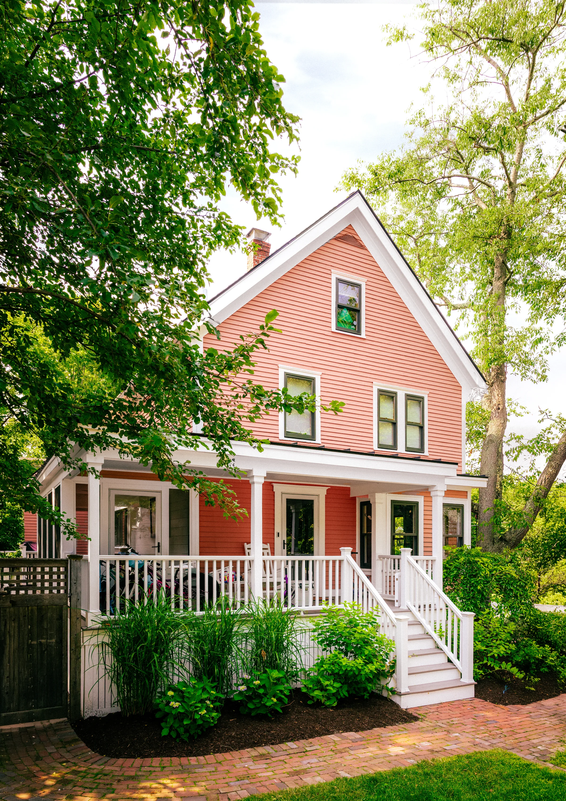 Historic coral-colored home with white porch trim and black window frames