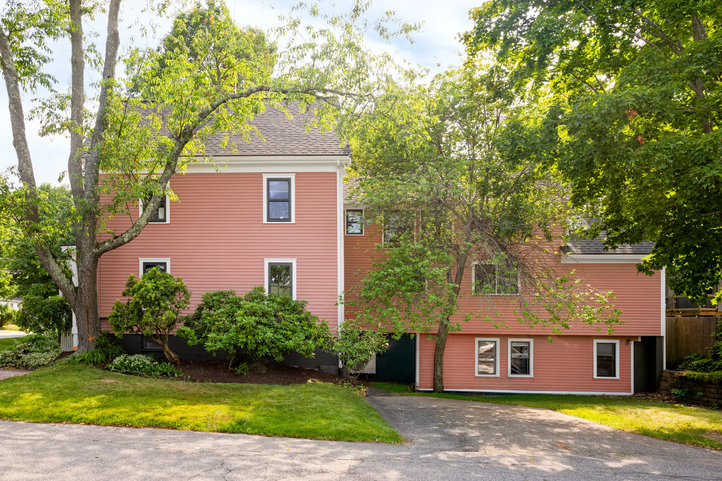 Wide side and rear elevation with coral siding, white window trim, and dark foundation