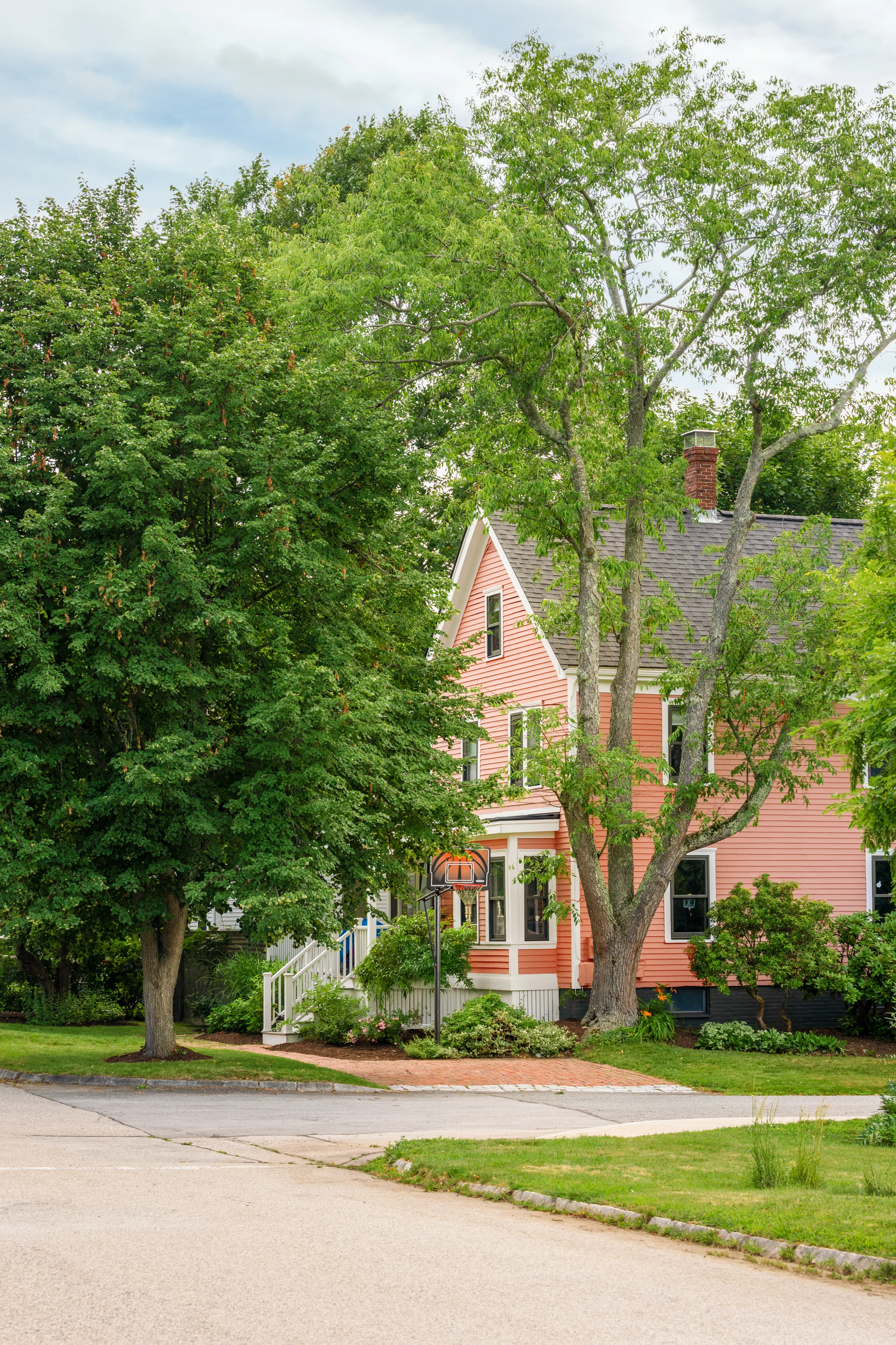 Side view of coral historic home surrounded by mature trees and landscaping