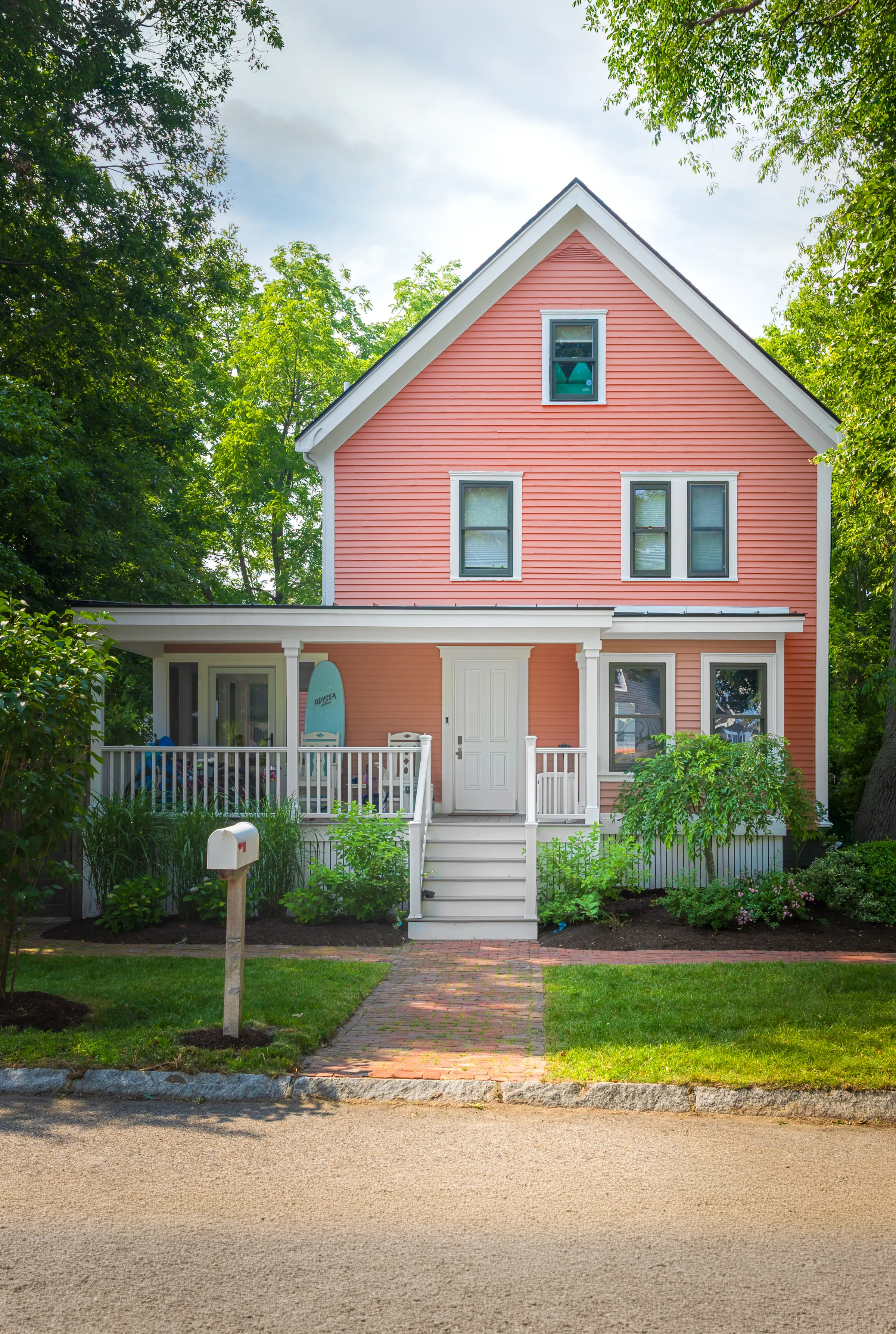 Front elevation with coral siding, white trim, porch, and centered steps