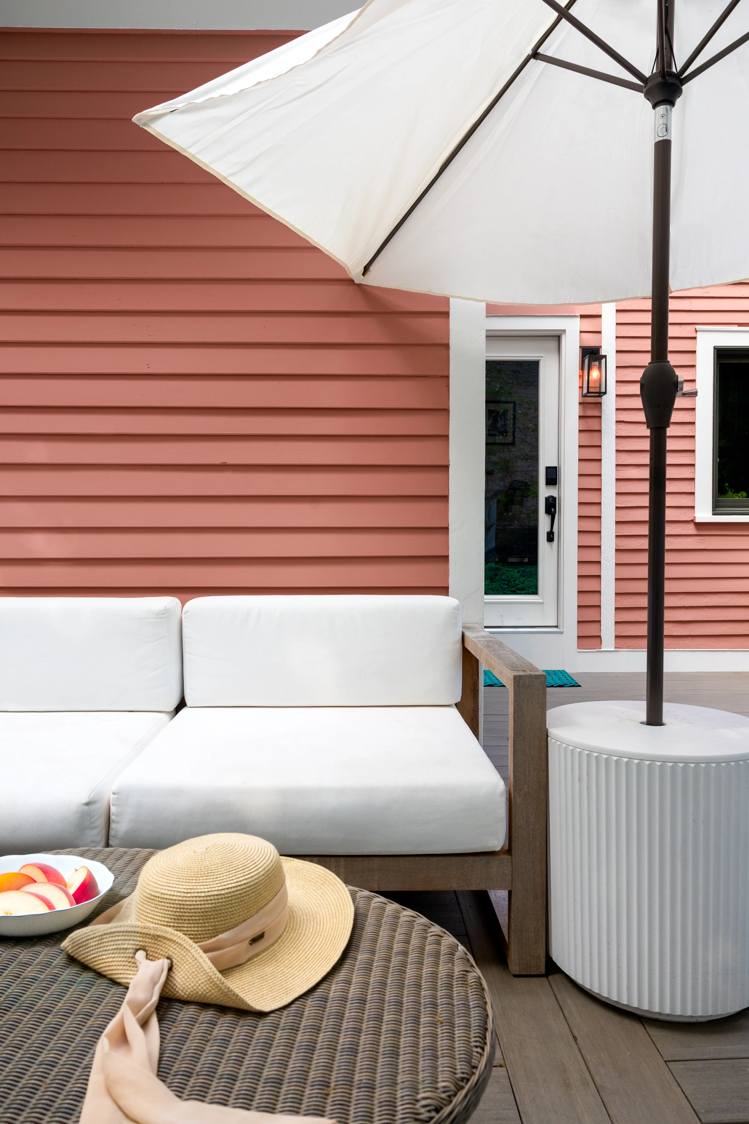 Patio seating beside coral clapboard siding and white-trimmed doors