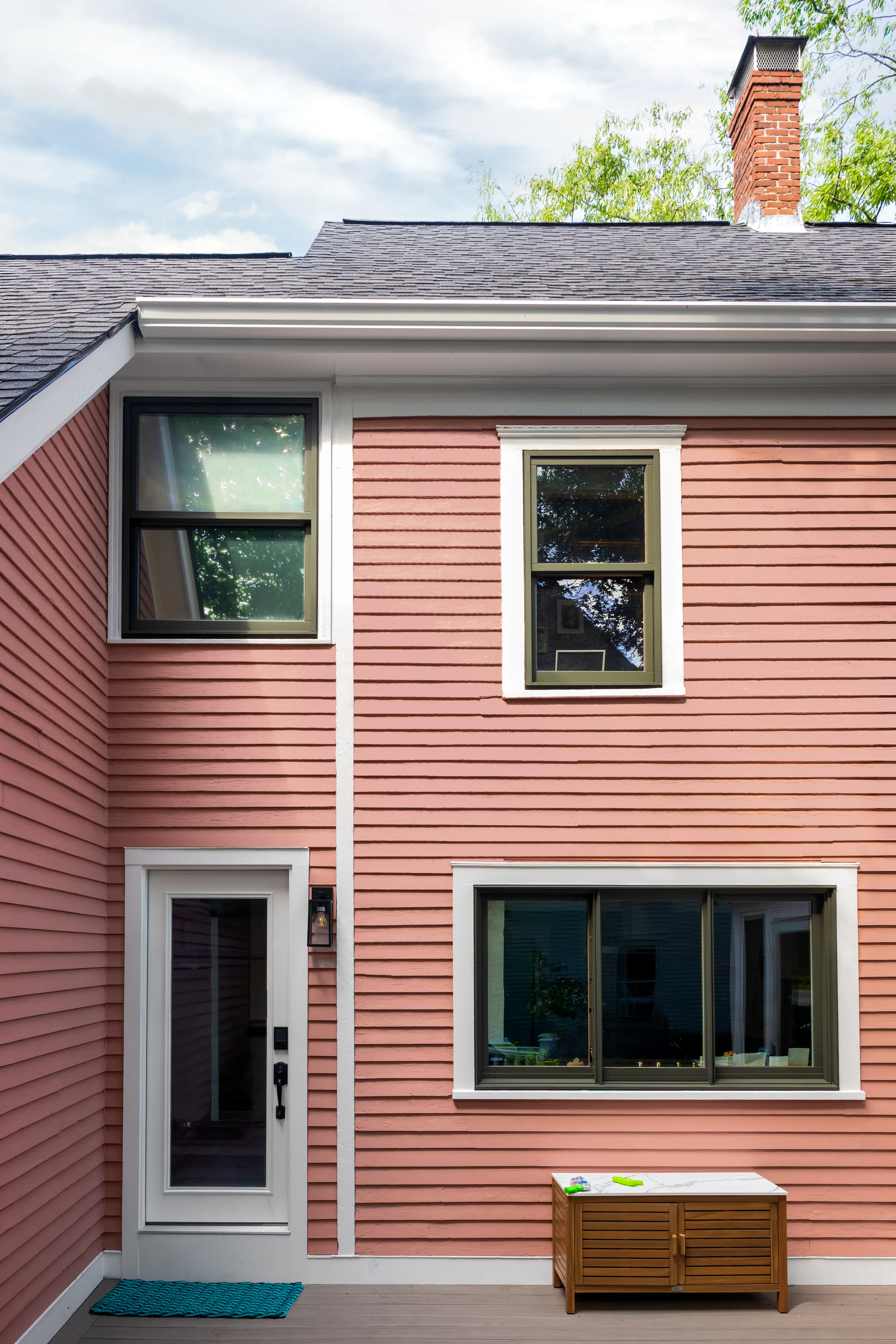 Rear exterior with coral clapboard siding, white trim, and dark-framed windows