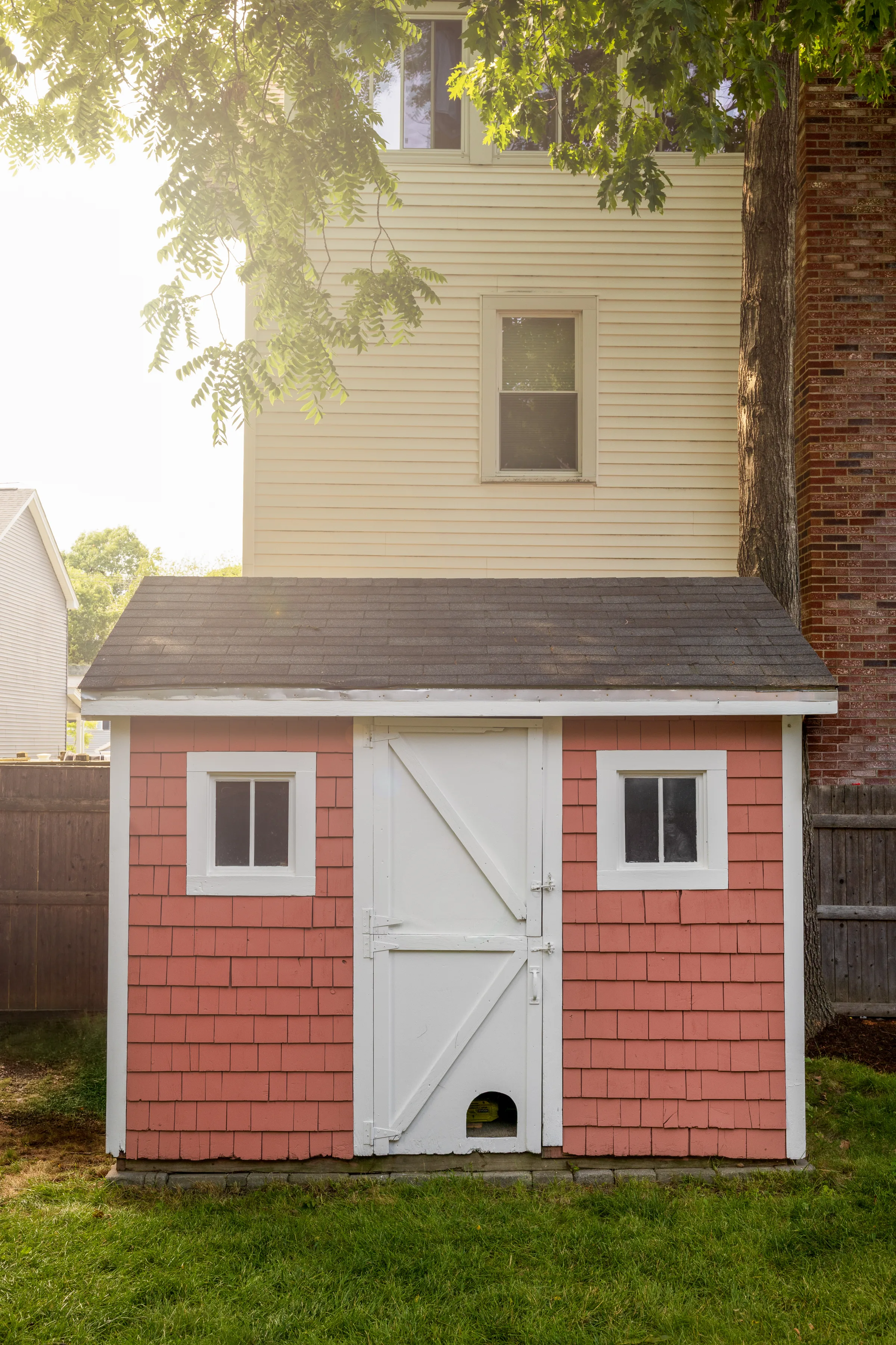Small detached shed with coral shingle siding, white trim, and double door