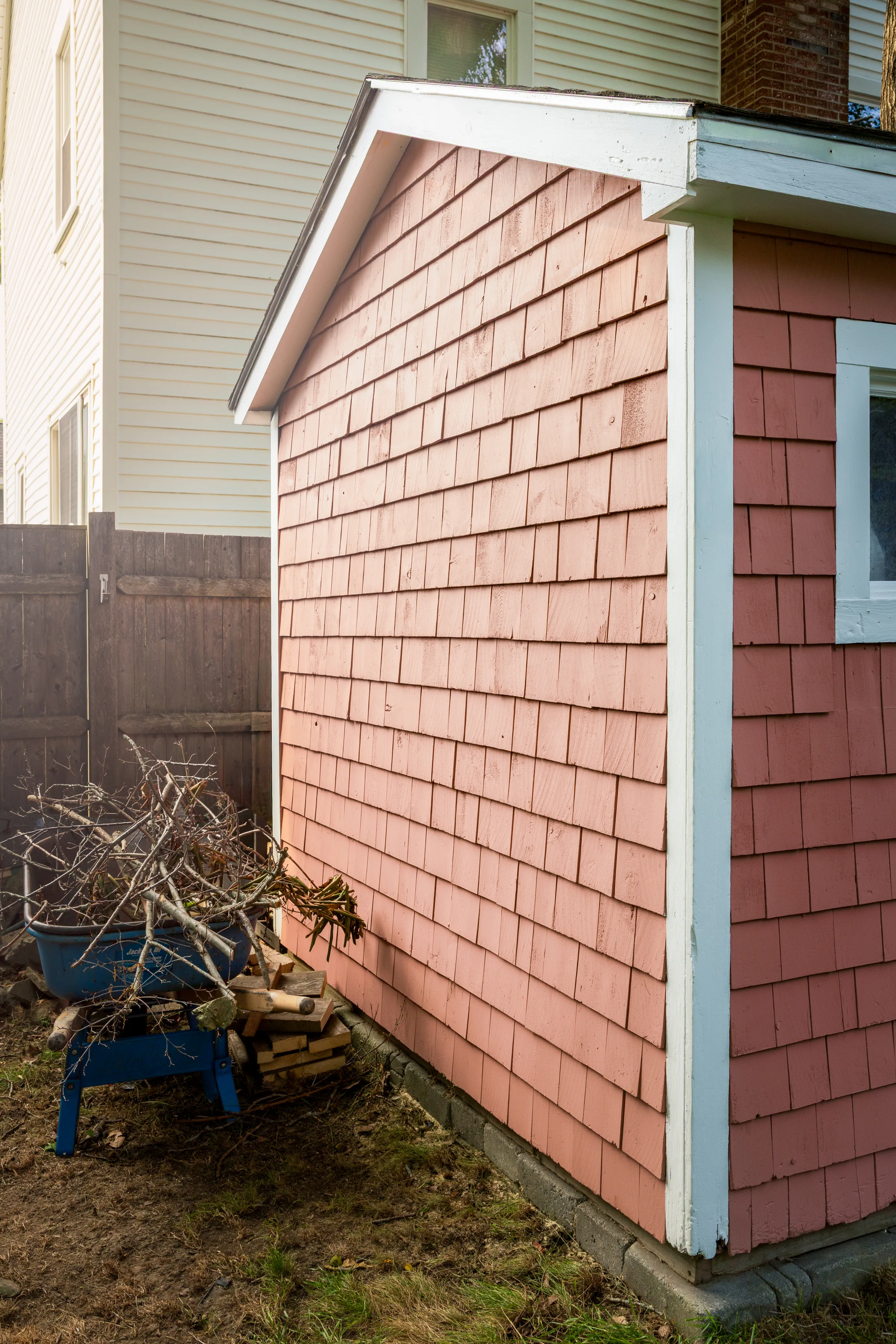Weathered coral shingle siding and white corner trim on a detached shed