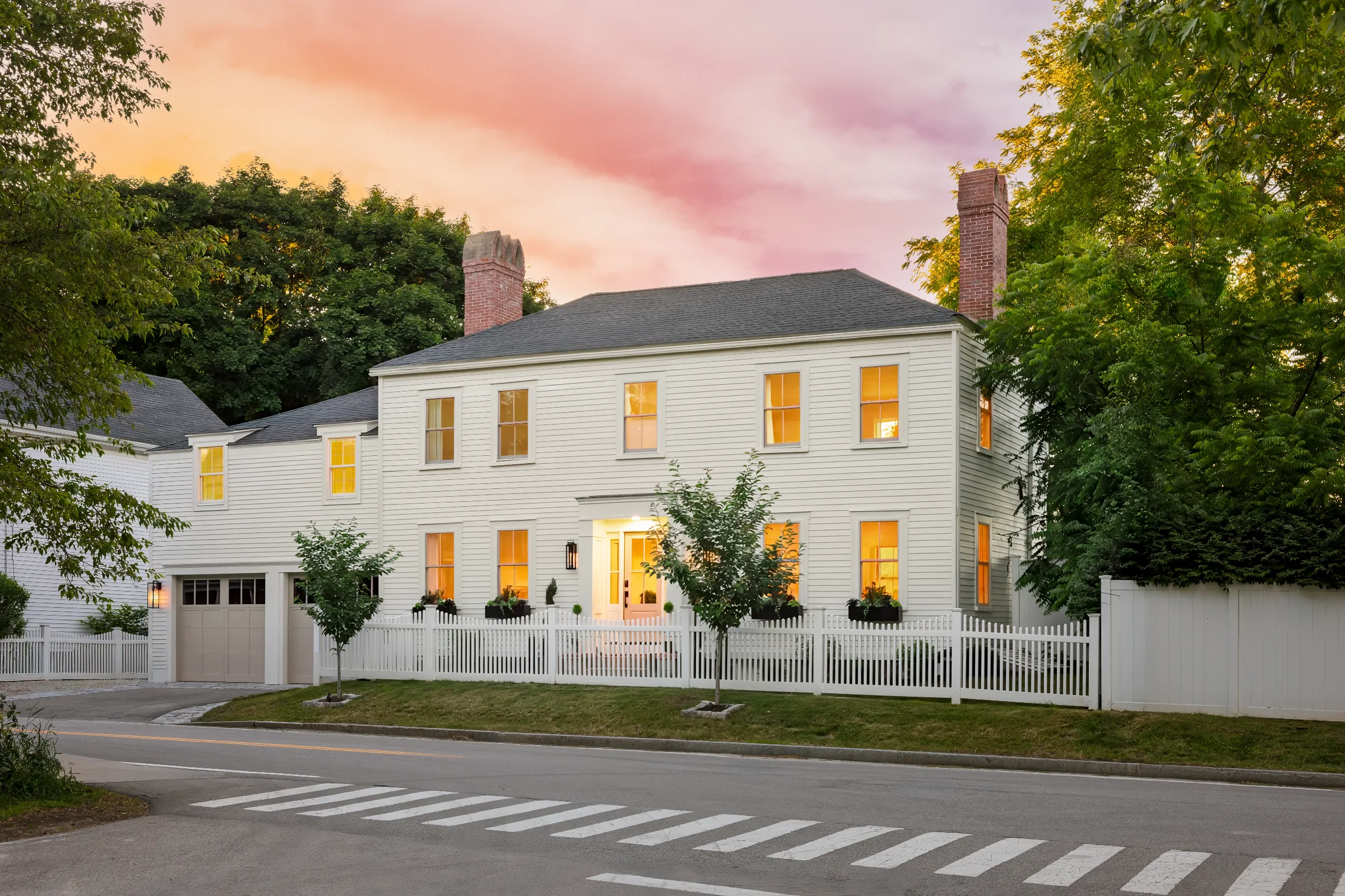 Front elevation of a light-painted two-story home and garage at sunset
